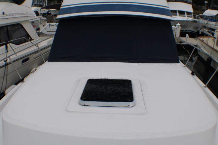 1986 Lynnwood Flybridge Sedan boat deck with hatch, docked among other vessels.