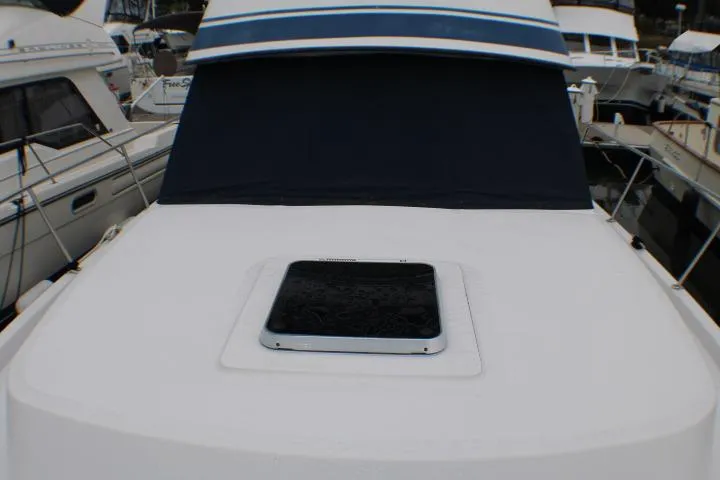 1986 Lynnwood Flybridge Sedan boat deck with hatch, docked among other vessels.