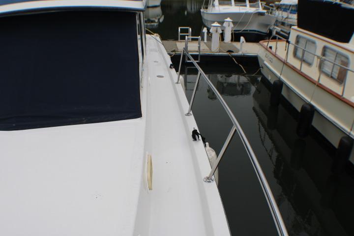 1986 Lynnwood Flybridge Sedan docked, showcasing sleek deck and railing design.