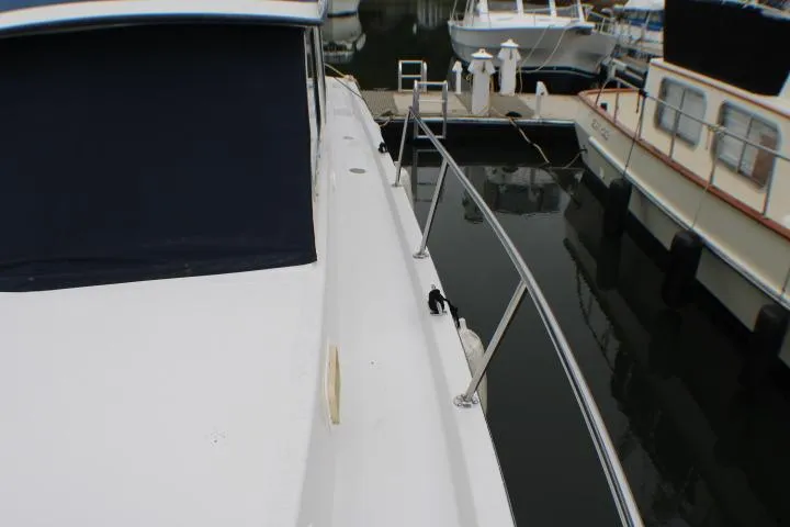 1986 Lynnwood Flybridge Sedan docked, showcasing sleek deck and railing design.