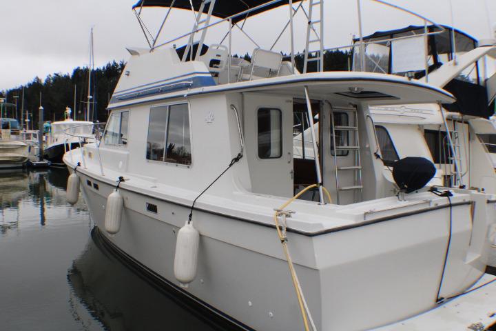 1986 Lynnwood Flybridge Sedan docked at marina, featuring classic design and spacious deck.