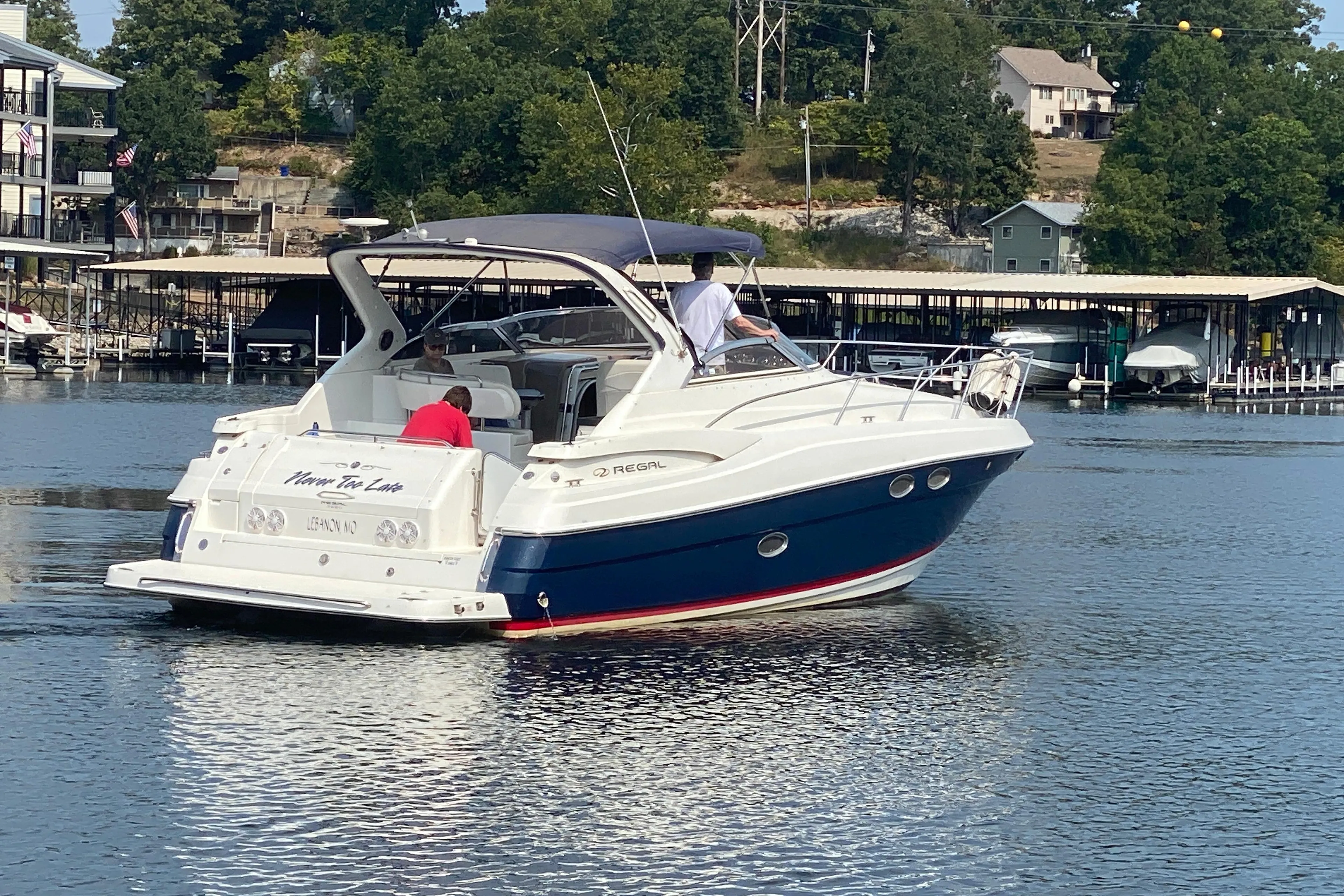 2004 Regal Commodore 3560 boat on a lake near docks and trees.