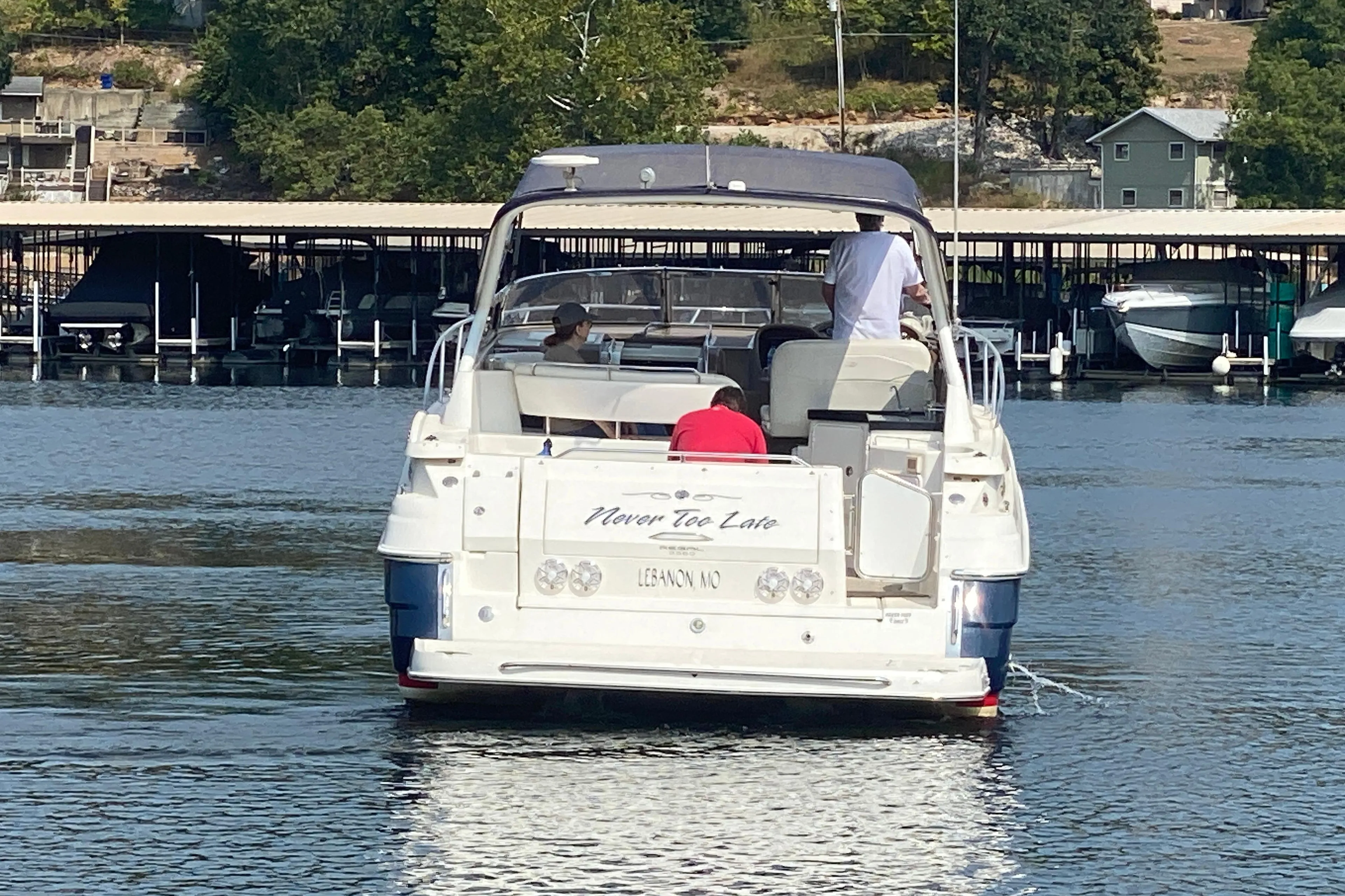 2004 Regal Commodore 3560 boat on water near dock, people onboard, trees in background.