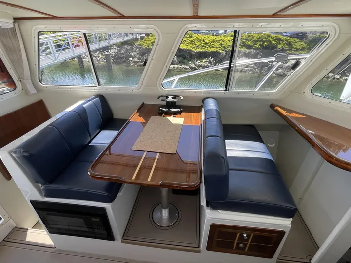 Ocean Roamer Yacht Photos Pics Interior of 2016 Lindell Ocean Roamer with blue seating and wooden table, overlooking water.