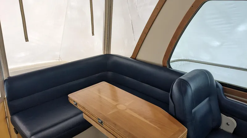 Sea Ranger Yacht Photos Pics Interior seating area of a 2008 Sabre 34 Express boat with blue upholstery and wooden table.
