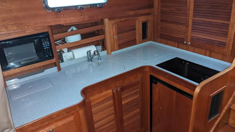 Sea Ranger Yacht Photos Pics 2008 Sabre 34 Express yacht kitchen with microwave, sink, stove, and wooden cabinetry.