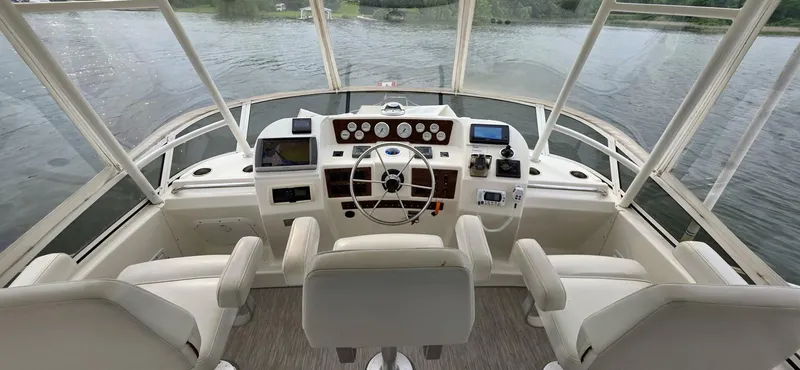  Yacht Photos Pics 2000 Silverton 453MY yacht helm with steering wheel and navigation instruments on a calm water backdrop.
