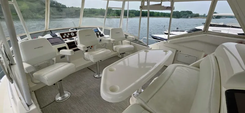  Yacht Photos Pics 2000 Silverton 453MY yacht interior with helm, seating, and table on a serene water backdrop.