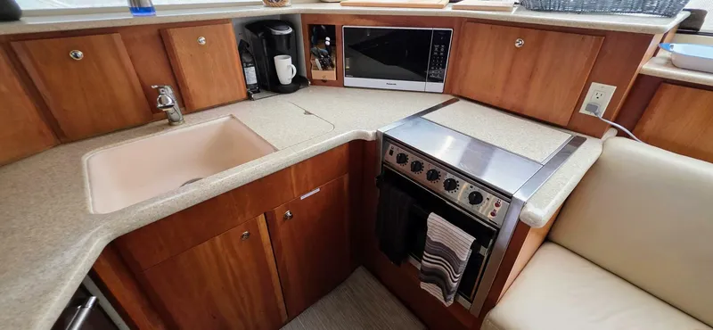  Yacht Photos Pics 2000 Silverton 453MY yacht kitchen with sink, stove, microwave, and wooden cabinetry.
