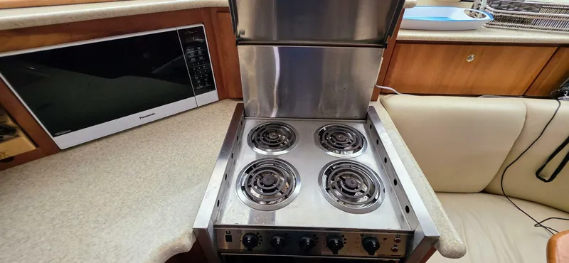  Yacht Photos Pics 2000 Silverton 453MY yacht kitchen with stove, microwave, and beige seating.