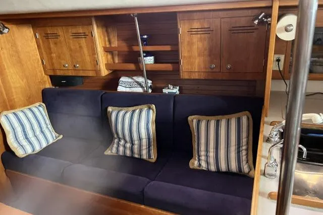 G Force Yacht Photos Pics 2004 J Boats J/133 interior with blue sofa, striped cushions, and wooden cabinetry.