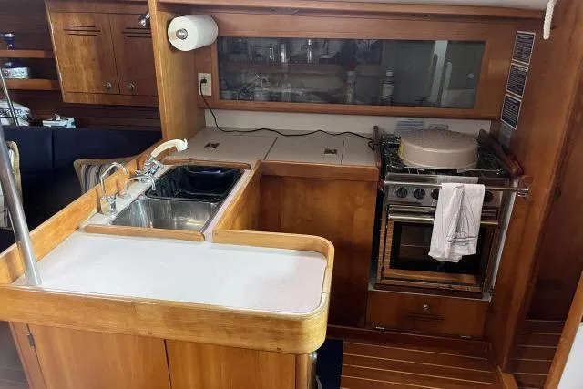 G Force Yacht Photos Pics 2004 J Boats J/133 yacht interior kitchen with sink, stove, and wooden cabinetry.