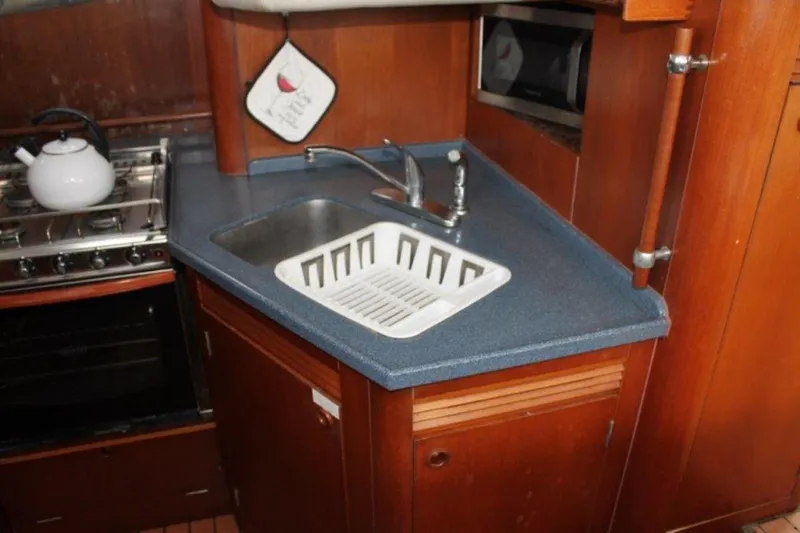 Mangata Yacht Photos Pics 2003 Lagoon 43 PC yacht kitchen with sink, stove, and wooden cabinetry.