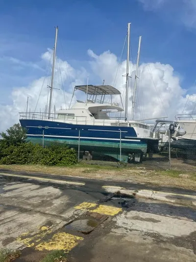 Mangata Yacht Photos Pics 2003 Lagoon 43 PC catamaran on land, blue hull, clear sky background.