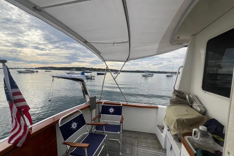 Semper Fi Yacht Photos Pics 2004 Sabre 36 Hardtop Sedan boat deck with chairs, American flag, and scenic harbor view.