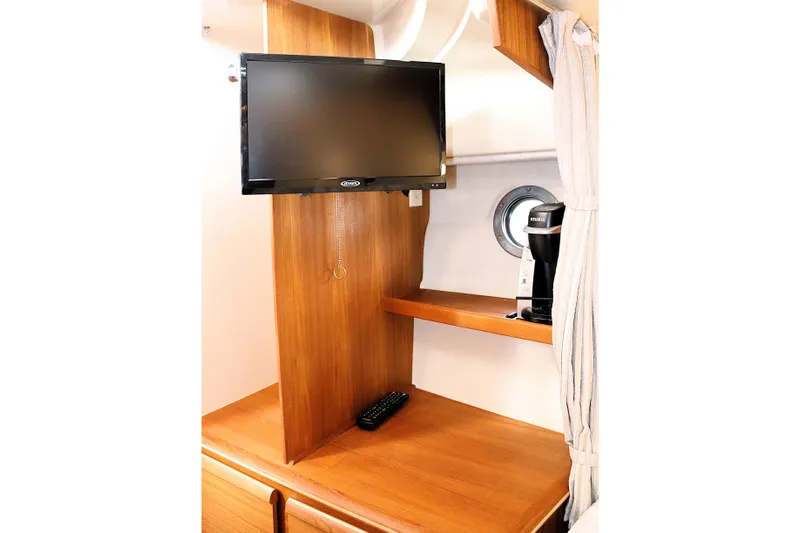 Tail Finn Yacht Photos Pics 2021 Ranger Tugs R-27 interior with TV, wooden cabinetry, and coffee maker.