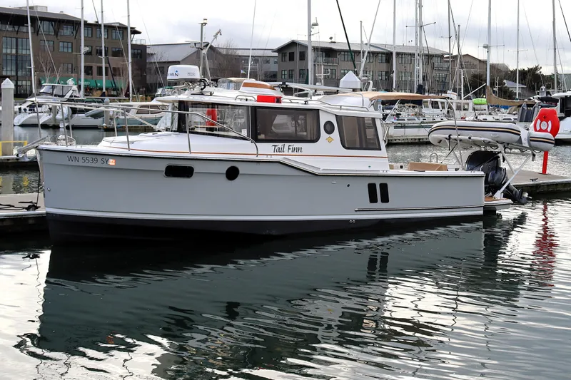 Tail Finn Yacht Photos Pics 2021 Ranger Tugs R-27 boat docked in marina, surrounded by other vessels.