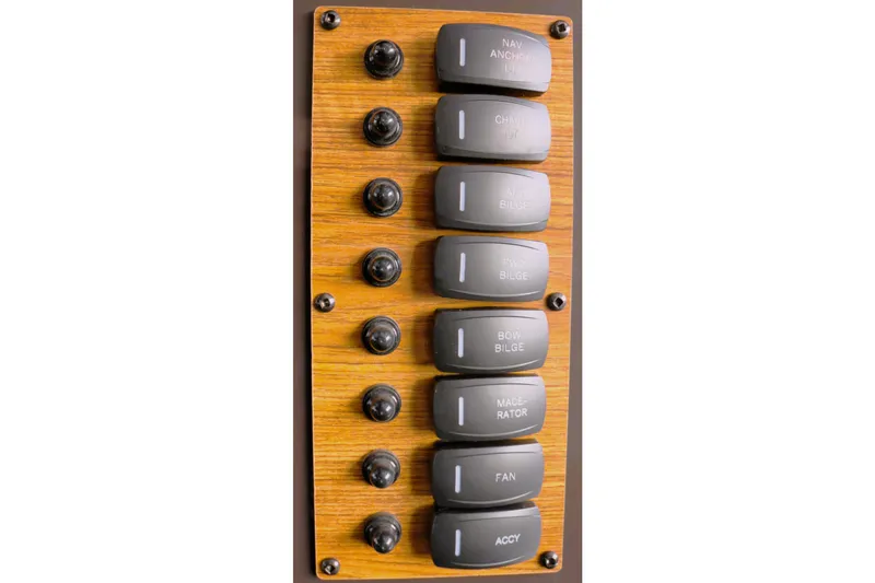 Tail Finn Yacht Photos Pics Control panel of 2021 Ranger Tugs R-27 with labeled switches on wood finish.