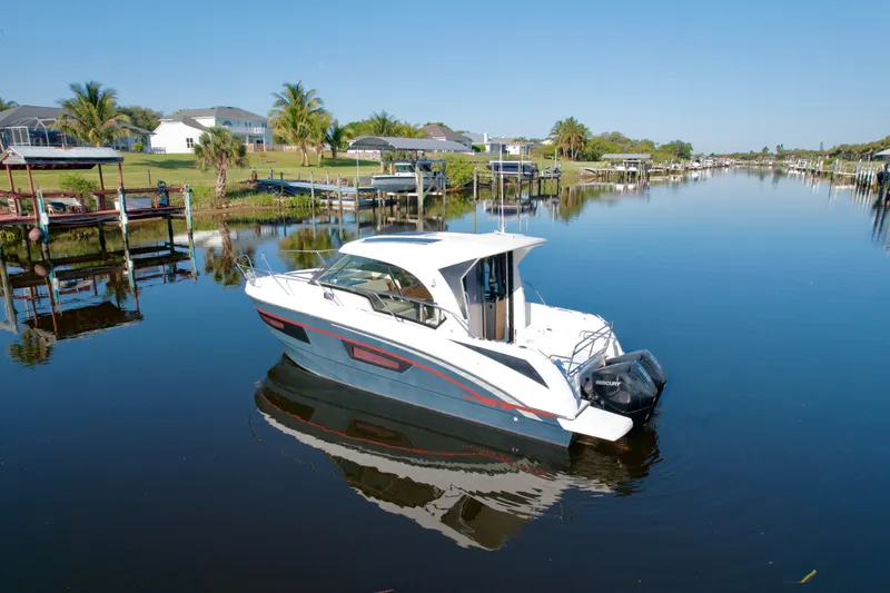  Yacht Photos Pics 2020 Beneteau Antares 9 OB boat on a calm canal, surrounded by lush greenery.