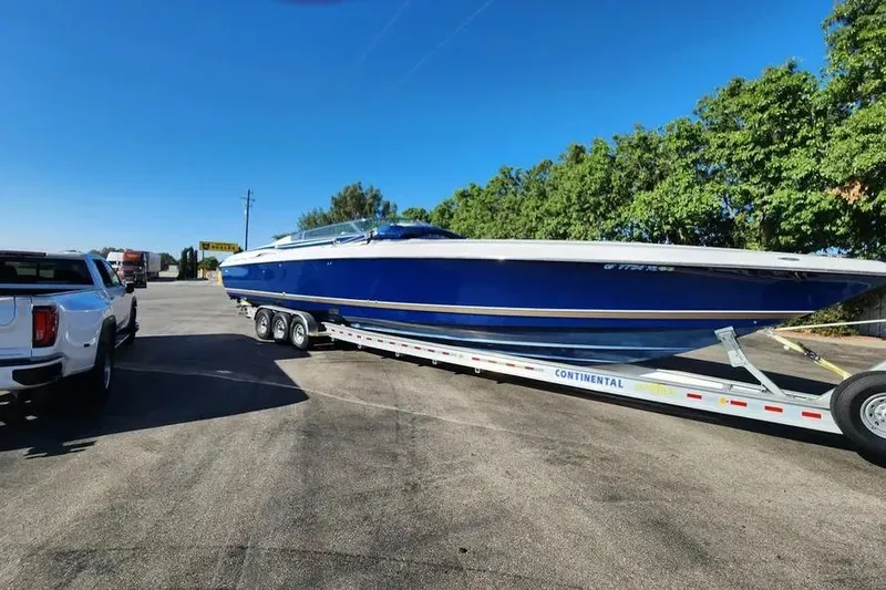  Yacht Photos Pics 2000 Donzi Daytona 45 boat on trailer, parked beside a white truck, under clear blue sky.
