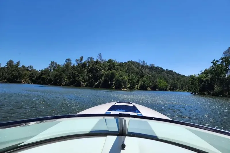  Yacht Photos Pics Donzi Daytona 45 boat cruising on a scenic lake, surrounded by lush greenery, under clear blue skies.