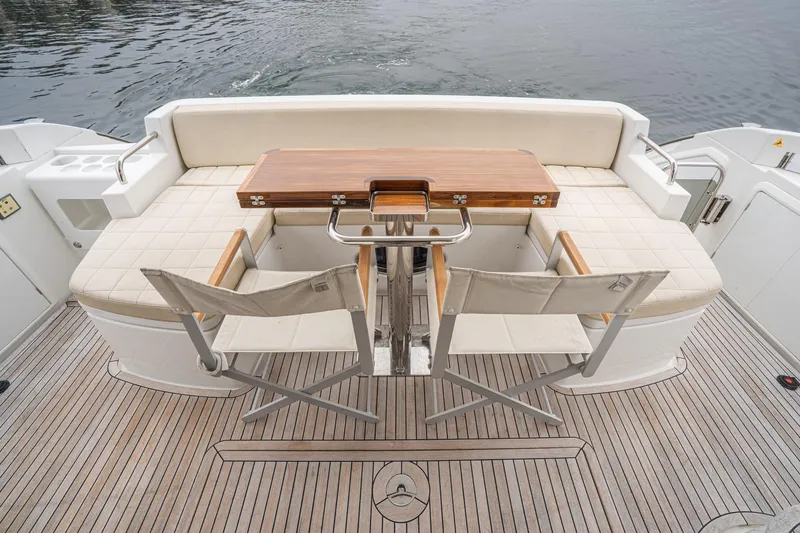  Yacht Photos Pics Luxury seating area on 2017 Azimut 54 Flybridge yacht with wooden table and chairs.
