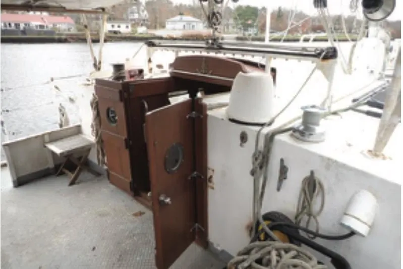 Cloud Chaser Yacht Photos Pics 67-foot steel ketch deck with open cabin door, ropes, and winch, docked by waterfront.