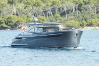 2018 Steeler 52s yacht cruising on clear blue water near a forested shoreline.