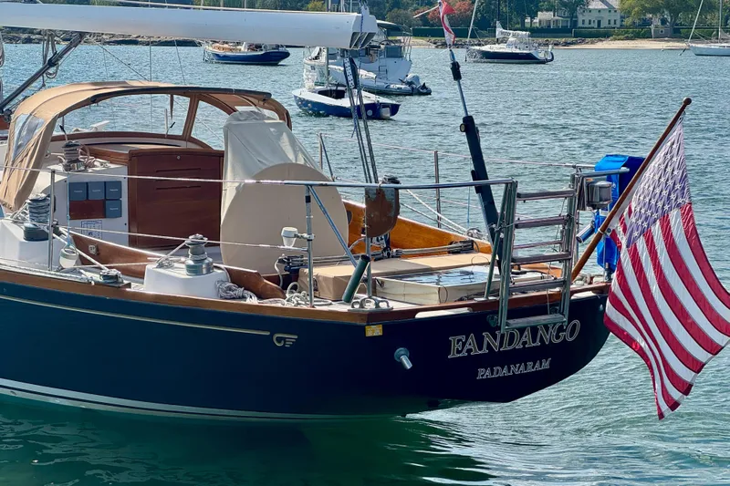 Fandango Yacht Photos Pics 1982 Hinckley Bermuda 40 MK III sailboat with American flag, docked in serene waters.