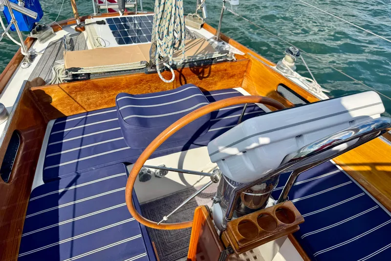 Fandango Yacht Photos Pics Cockpit of 1982 Hinckley Bermuda 40 MK III sailboat with wooden wheel and blue cushions.
