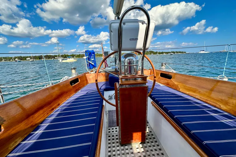 Fandango Yacht Photos Pics Hinckley Bermuda 40 MK III sailboat cockpit with wooden wheel, blue cushions, and ocean view.
