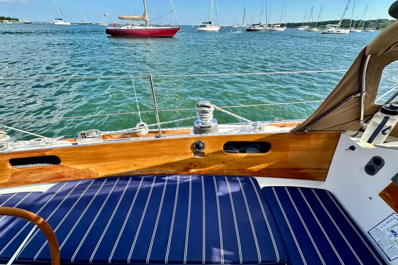 Fandango Yacht Photos Pics Hinckley Bermuda 40 MK III sailboat, 1982, with blue-striped seating, docked in a scenic harbor.