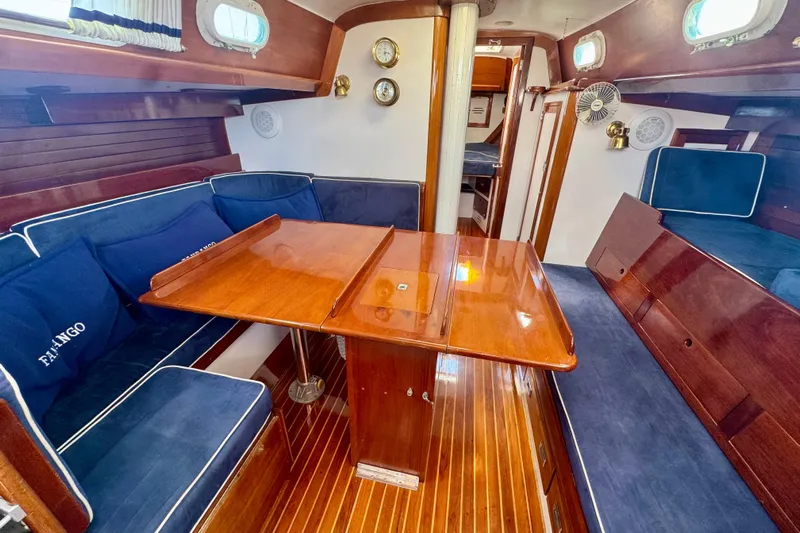 Fandango Yacht Photos Pics Interior of 1982 Hinckley Bermuda 40 MK III sailboat with wooden table and blue seating.