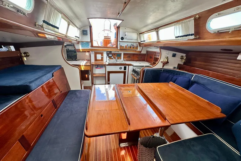 Fandango Yacht Photos Pics Interior of 1982 Hinckley Bermuda 40 MK III sailboat with wooden furnishings and blue cushions.