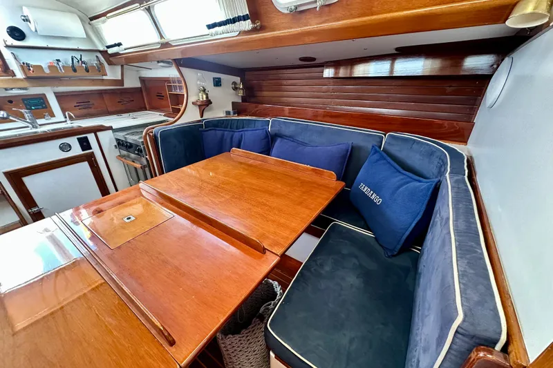 Fandango Yacht Photos Pics Hinckley Bermuda 40 MK III 1982 interior with wooden table, blue cushions, and kitchen area.