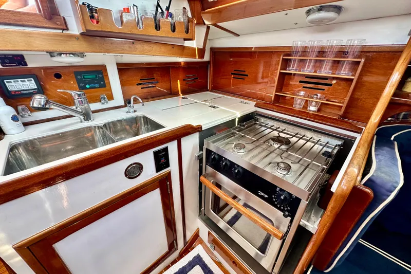 Fandango Yacht Photos Pics Hinckley Bermuda 40 MK III 1982 yacht kitchen with stove, sink, and wooden cabinetry.