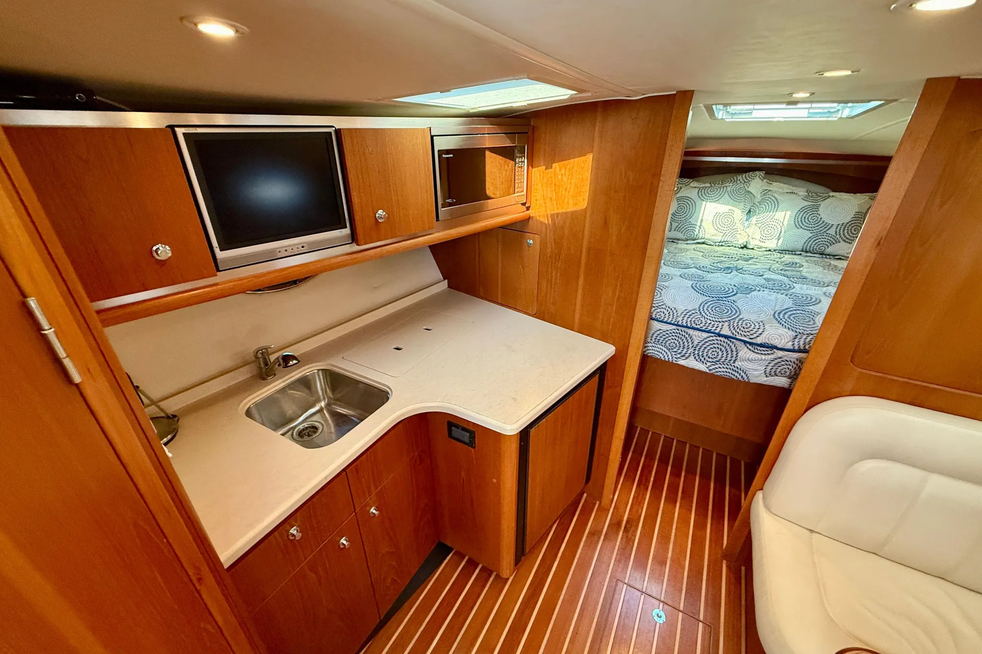 Luxurious 2005 Tiara 3600 Open yacht interior with kitchenette and cozy sleeping area.
