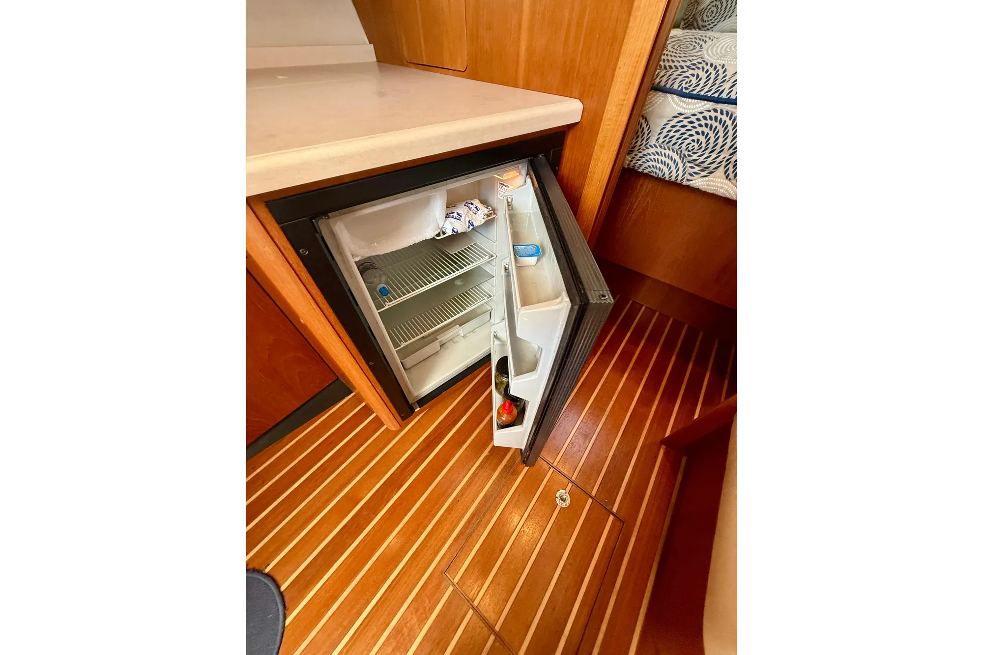 Open mini fridge in 2005 Tiara 3600 Open yacht interior, wooden flooring visible.