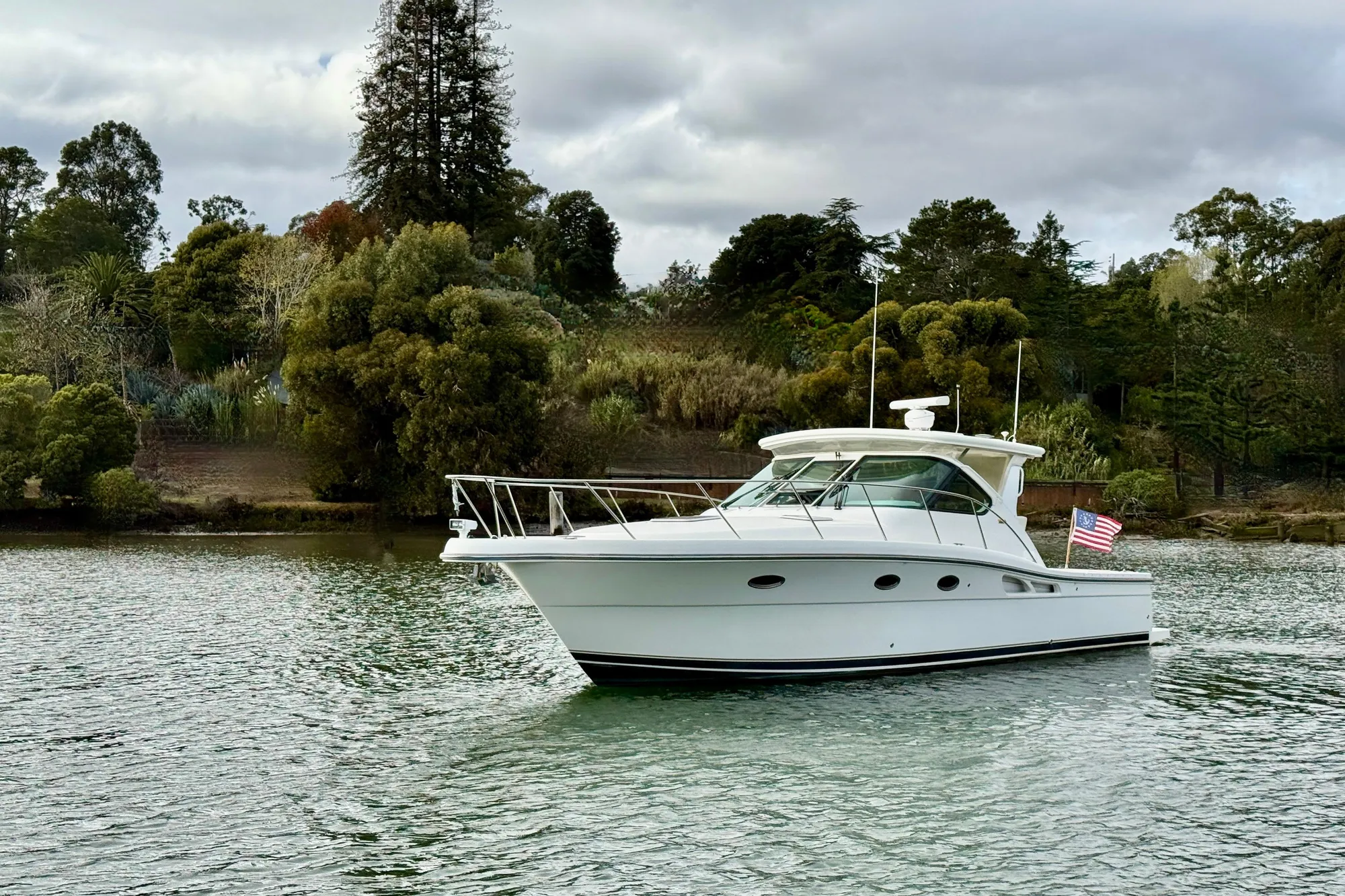 2005 Tiara 3600 Open yacht on a serene lake with lush greenery.
