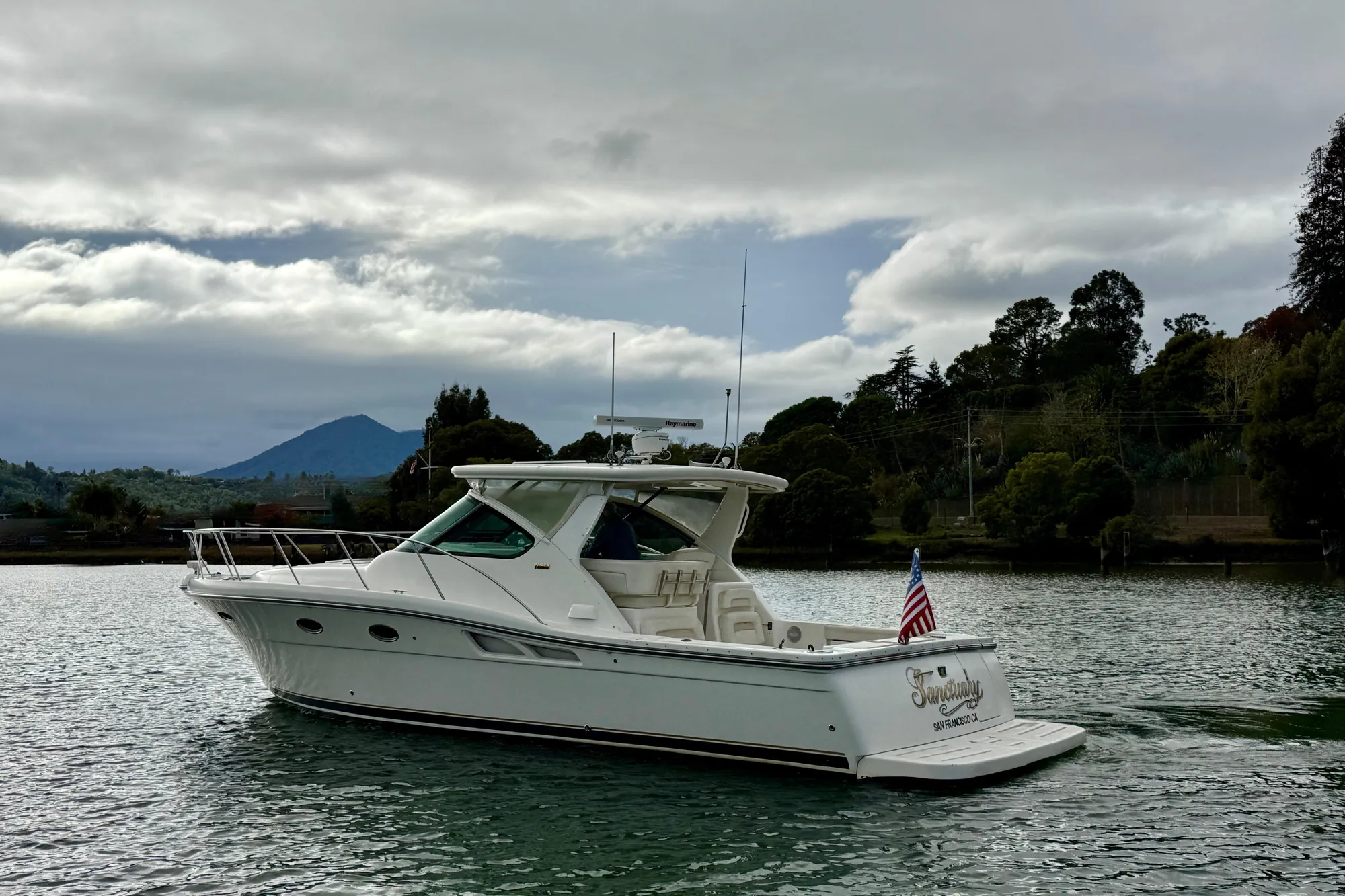 2005 Tiara 3600 Open yacht cruising on a scenic waterway with lush greenery.