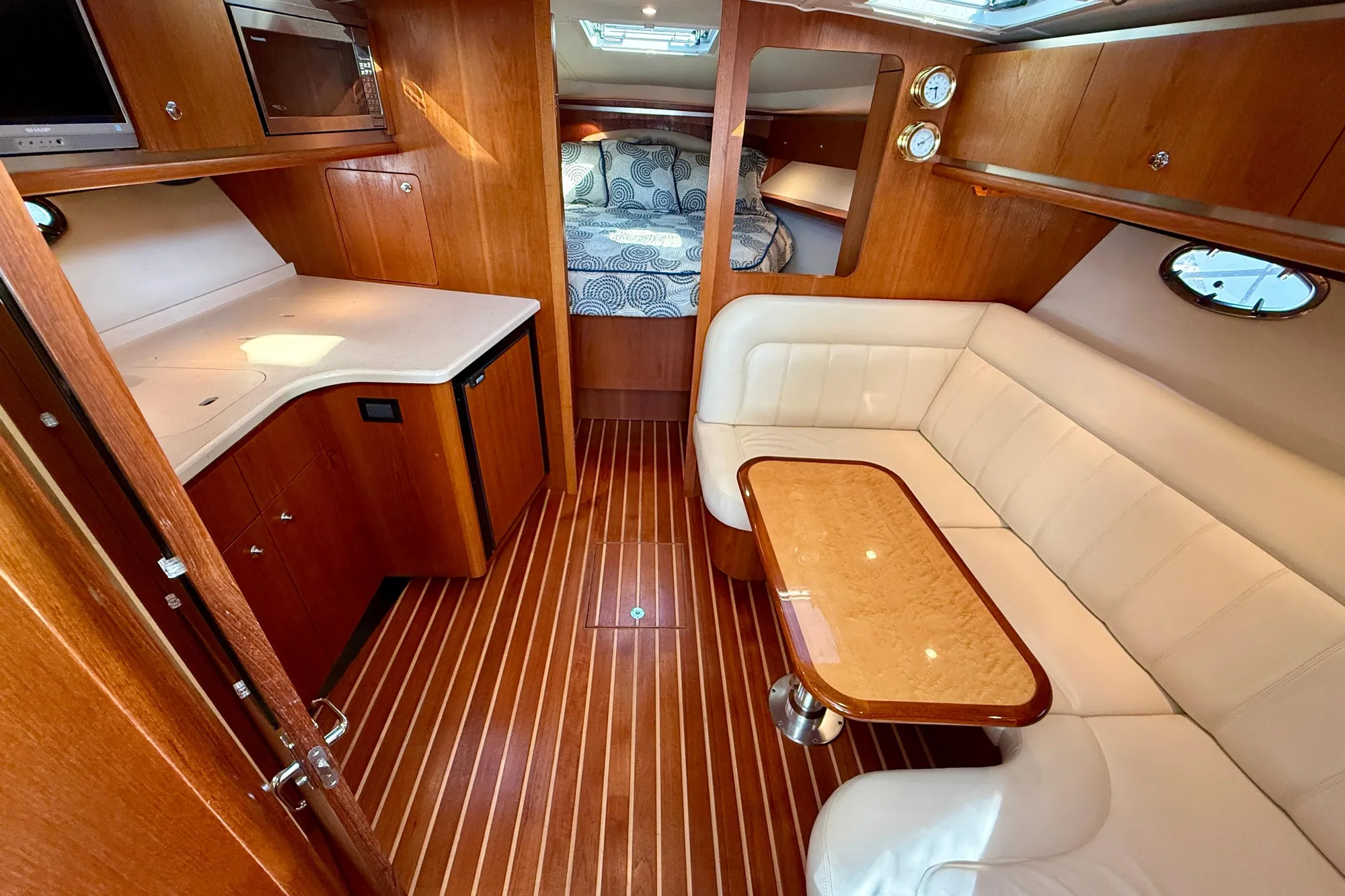 2005 Tiara Yachts 3600 Open interior with wood finish, white seating, and compact kitchen.