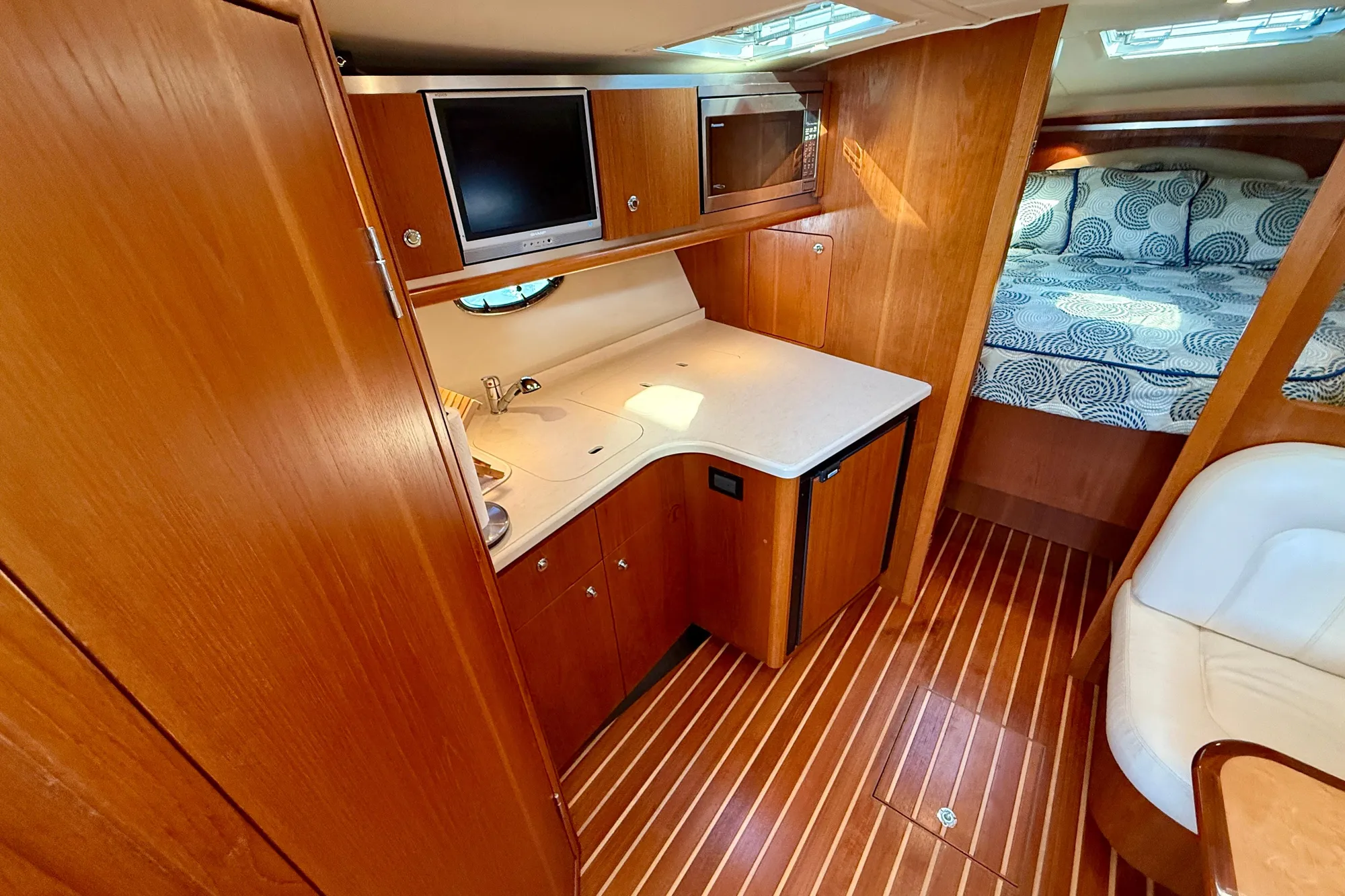 2005 Tiara Yachts 3600 Open interior with wood finish, kitchenette, and cozy sleeping area.