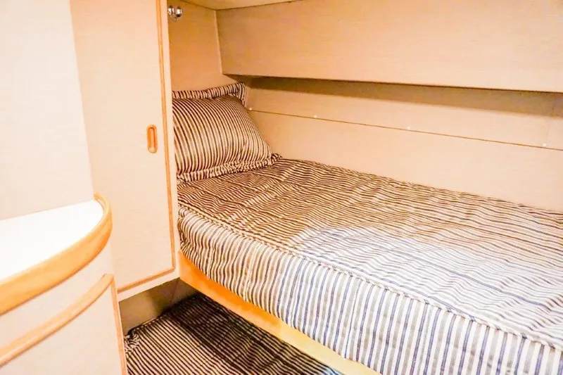 Wonderer Yacht Photos Pics 1987 Bertram 54 Convertible cabin with striped bedding and wooden cabinetry.