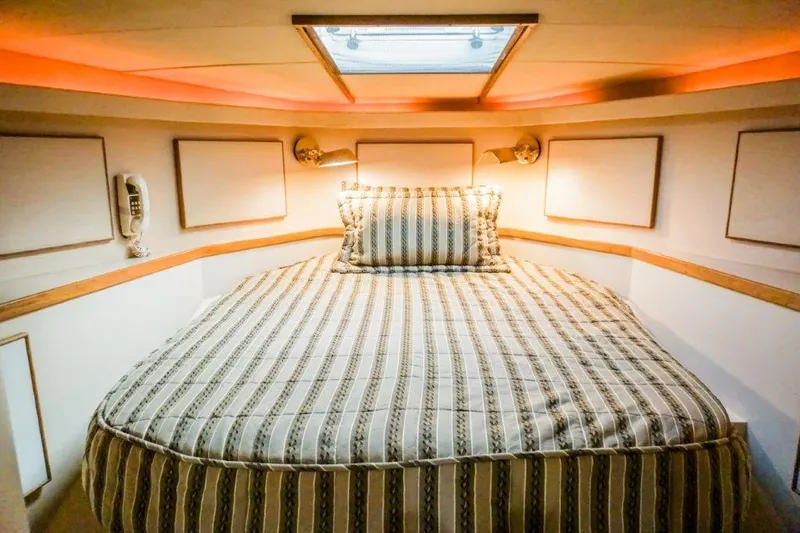 Wonderer Yacht Photos Pics Cozy bedroom in 1987 Bertram 54 Convertible yacht with striped bedding and warm lighting.