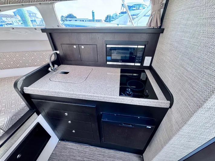 Seanior Moment Yacht Photos Pics 2022 Stamas 370 Aegean yacht interior kitchen with sink, stove, and microwave.