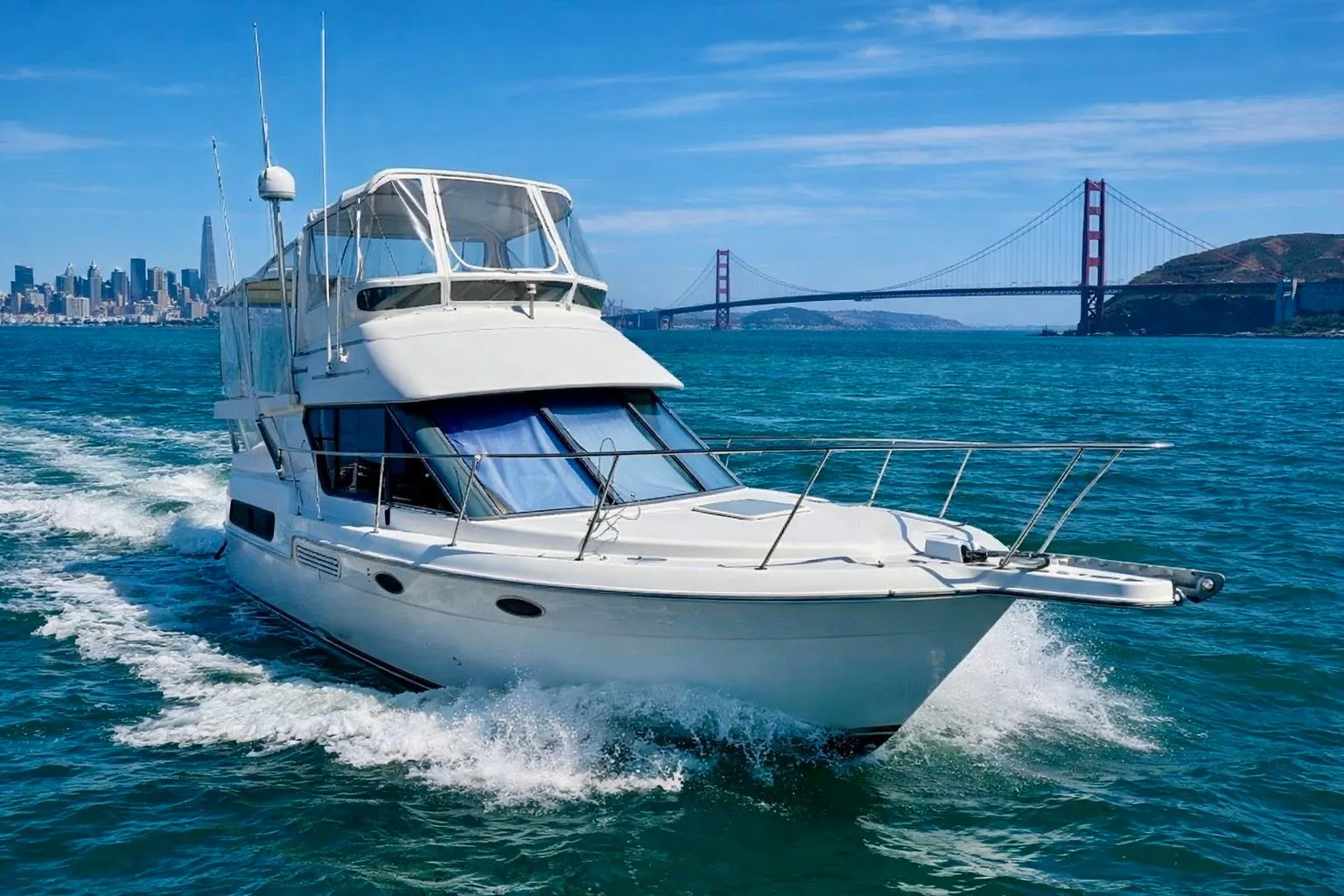 1997 Carver 325 Aft Cabin Motor Yacht cruising near iconic bridge and city skyline.