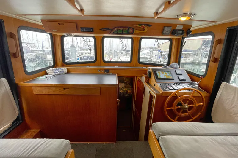 Lagnaf Yacht Photos Pics Cozy 2002 Nordic Tug 37 pilothouse with wooden helm and navigation equipment.