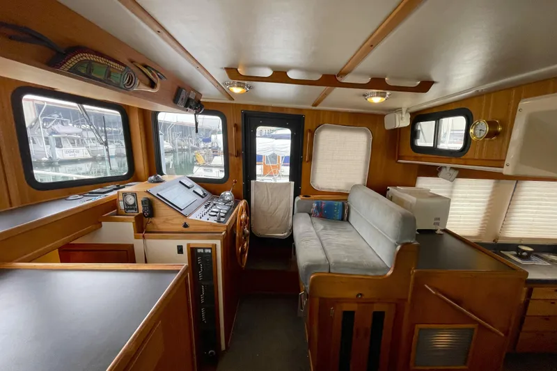 Lagnaf Yacht Photos Pics Interior of 2002 Nordic Tug 37, featuring helm, seating, and wooden cabinetry.