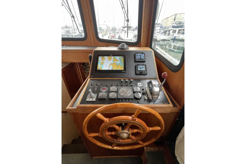 Lagnaf Yacht Photos Pics Control panel of a 2002 Nordic Tug 37 with navigation instruments and wooden steering wheel.