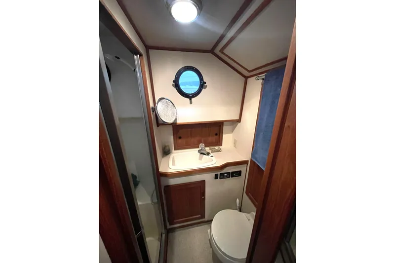 Lagnaf Yacht Photos Pics Bathroom interior of 2002 Nordic Tug 37 with porthole, sink, and toilet.